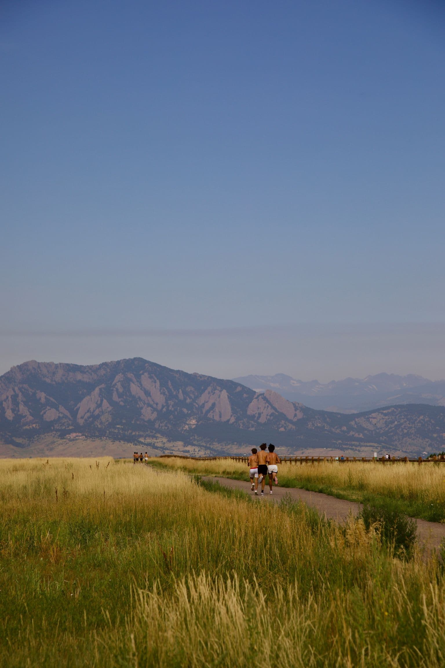 Runners on an open gravel trail through golden grassland